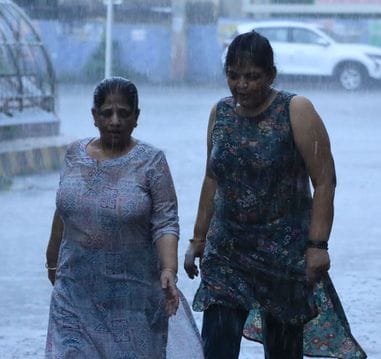 रोहतक में बारिश के दौरान अपने गंतव्य की ओर जाते दोपहिया महिला वाहन चालक। संवाद