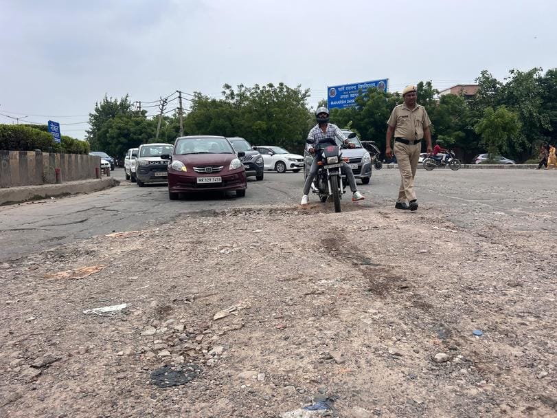 रोहतक के दिल्ली बाइपास चौक पर सड़क की खस्ता हालत से जाते राहगीर व वाहन चालक। संवाद