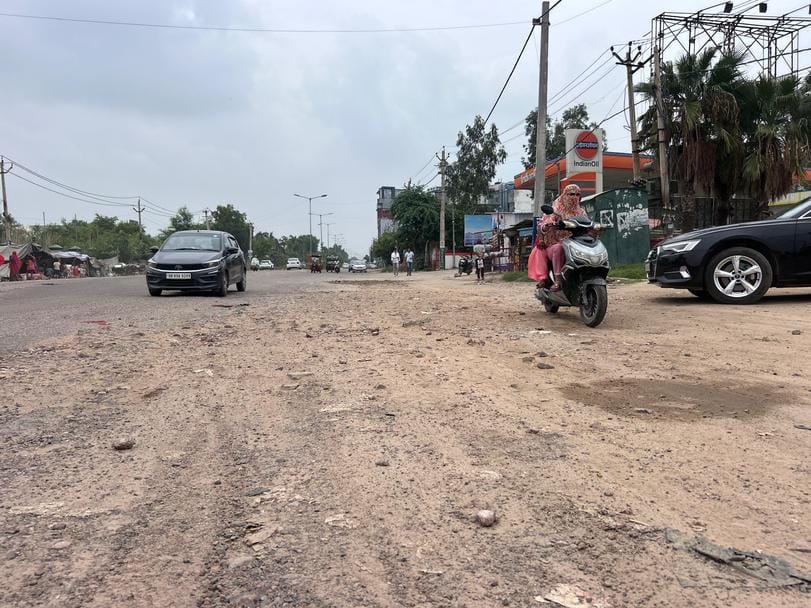 रोहतक के दिल्ली बाइपास चौक पर सड़क की खस्ता हालत से जाते राहगीर व वाहन चालक। संवाद
