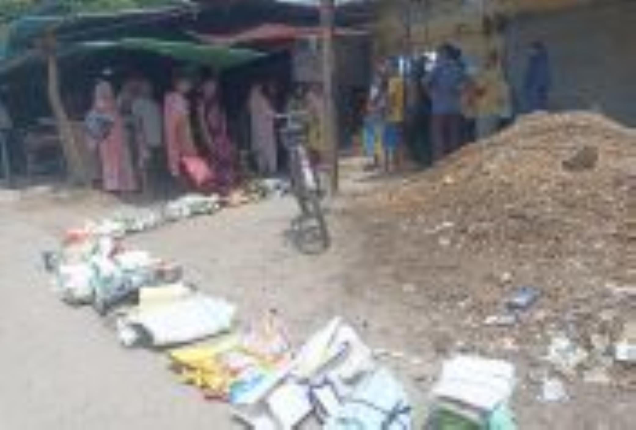 बैग जमीन पर रखकर छांव में खड़े उपभोक्ता।