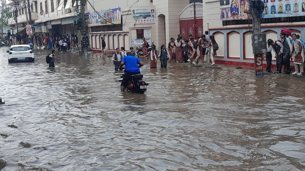 28जेएनडी37: नरवाना के ओल्ड कोर्ट रोड पर बरसात के बाद जमा हुए पानी से स्कूली बच्चों को लेकर आते 