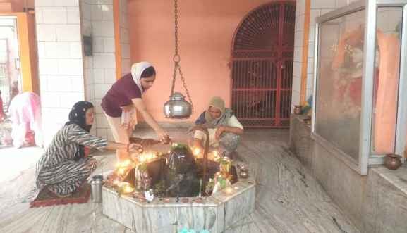 28jjrp06- झज्जर। शहर के संकट मोचन महाकाल शिव मंदिर में शिवलिंग पर जलाभिषेक करते हुए श्रद्धा