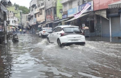 माधवपुरम में बारिश के कई घंटे बाद जर्जर सड़क पर जलभराव और किनारे कूड़े का ढेर