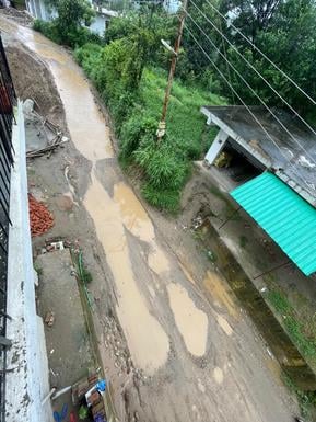 अणु से बड़ू संपर्क मार्ग पर पानी जमा होने से बने तालाब के बीच से होकर गुजरता टैंपों। स्रोत: जागर अणु से बड़ू संपर्क मार्ग पर पानी जमा होने से बने तालाब के बीच से होकर गुजरता टैंपों। स्रोत: जागर