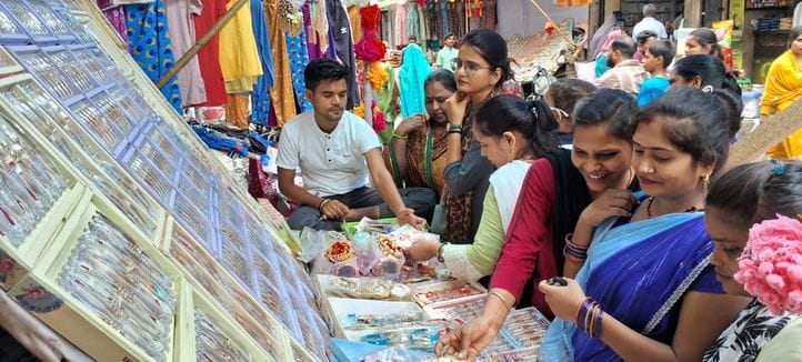 बजार में सजी राखी की दुकान पर राखियां  खरीदती बहनें। संवाद