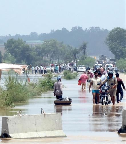 बिजनौर में मेरठ-पौड़ी नेशनल हाईवे के ऊपर से बह रहे पानी को जेसीबी में बैठक पार करते लोग। बिजनौर में मेरठ-पौड़ी नेशनल हाईवे के ऊपर से बह रहे पानी को जेसीबी में बैठक पार करते लोग।