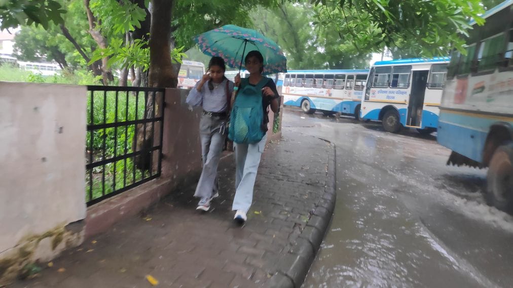 रोहतक अड्डे पर बारिश के बाद हुए जलभराव से गुजरतीं बसें। संवाद