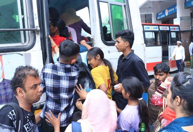 रोहतक से बस अड्डा पर बस में सवार होने के मशक्कत करते यात्री। संवाद