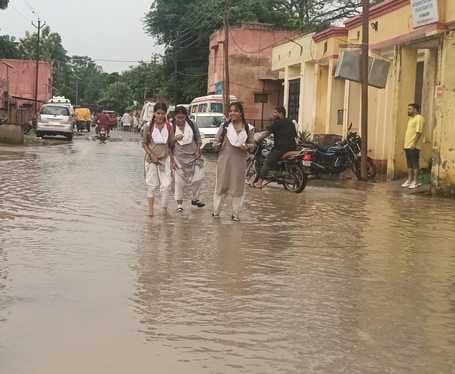 जलभराव की वजह से बच्चे को कंधे पर लेकर जाती महिला। संवाद