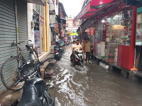 जलभराव की वजह से बच्चे को कंधे पर लेकर जाती महिला। संवाद