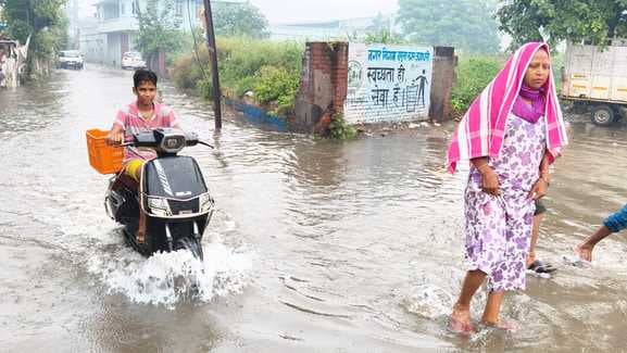 बर्तन बाजार में हुए जलभराव में खराब हुई एक्टिवा को लेकर जाता व्यक्ति। संवाद बर्तन बाजार में हुए जलभराव में खराब हुई एक्टिवा को लेकर जाता व्यक्ति। संवाद