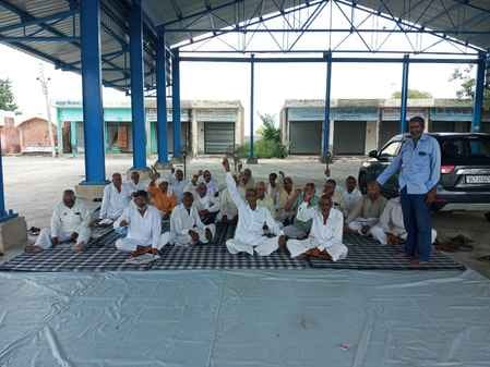 बाढड़ा अनाज मंडी में मुआवजे की मांग के लिए धरने पर बैठे किसान।