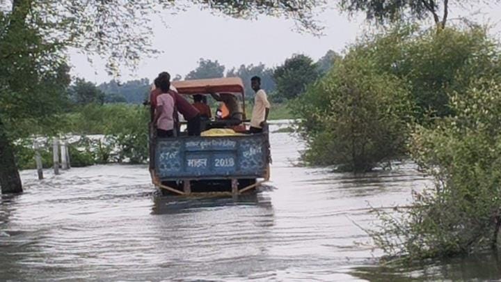 बाढ़ के बीच से जाते लोग।