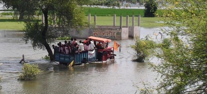 बाढ़ के बीच से जाते लोग।