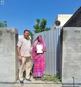 सरकारी सबूत मिलने के बाद घर के दरवाजे पर खड़े घर के मालिक स्रोत नगर पंचायत