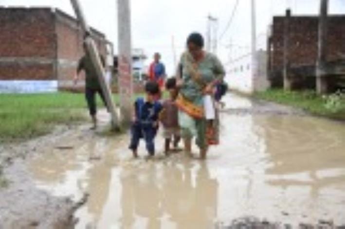 जलभराव से गुजरते लोग। जलभराव से गुजरते लोग।