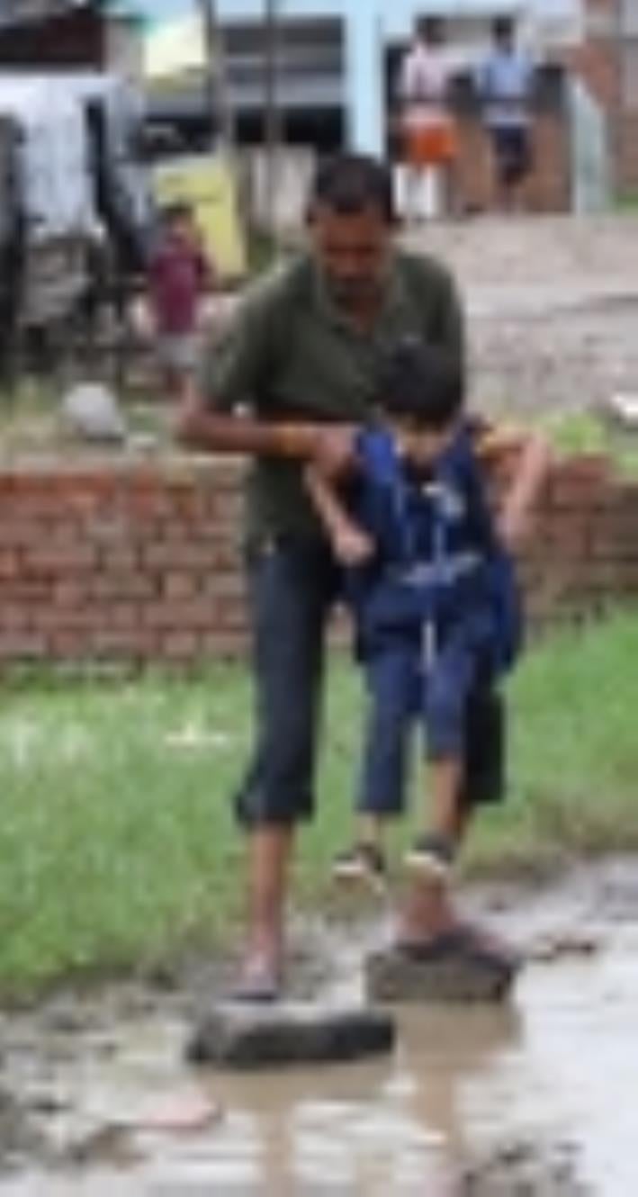जलभराव से गुजरते लोग। जलभराव से गुजरते लोग।