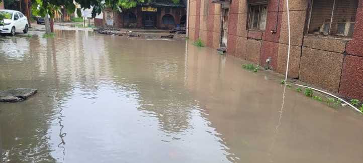 शहर के नगला पोता मोहल्ला में जलभराव से होकर गुजरती महिला। संवाद