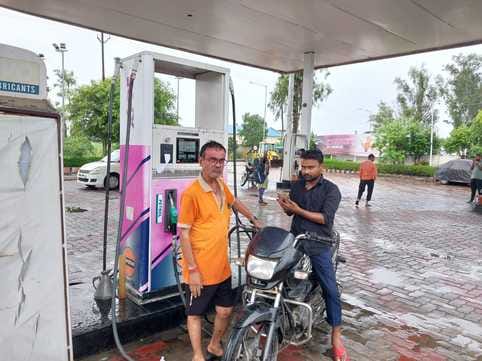 बीसलपुर के बिलसंडा रोड स्थित पंप के बाहर हेलमेट लेकर खड़ा कर्मचारी। संवाद