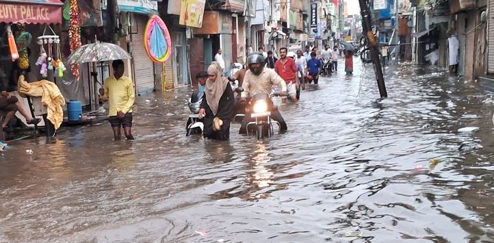 जोगीपुरा में स्थित दुकान में भरा पानी, बाहर बैठे दुकानदार। संवाद