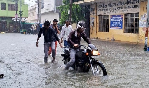 जोगीपुरा में स्थित दुकान में भरा पानी, बाहर बैठे दुकानदार। संवाद