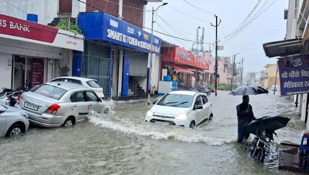जोगीपुरा में स्थित दुकान में भरा पानी, बाहर बैठे दुकानदार। संवाद