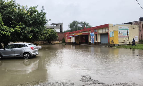 जोगीपुरा में स्थित दुकान में भरा पानी, बाहर बैठे दुकानदार। संवाद