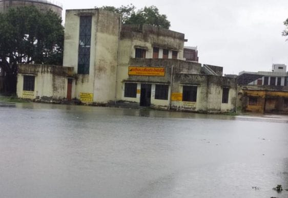 जोगीपुरा में स्थित दुकान में भरा पानी, बाहर बैठे दुकानदार। संवाद