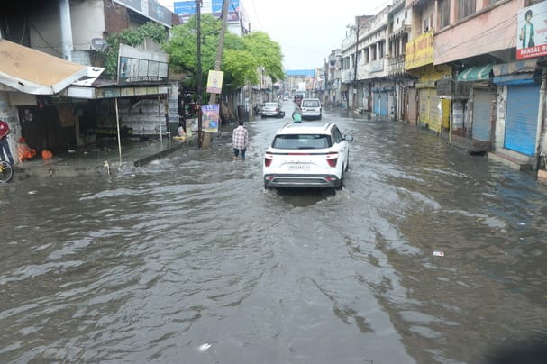 शक्ति नगर में बारिश में हुए जलभराव के बीच गुजरती कार। संवाद