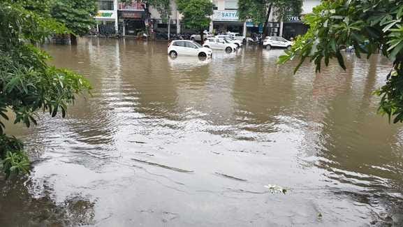 शक्ति नगर में बारिश में हुए जलभराव के बीच गुजरती कार। संवाद