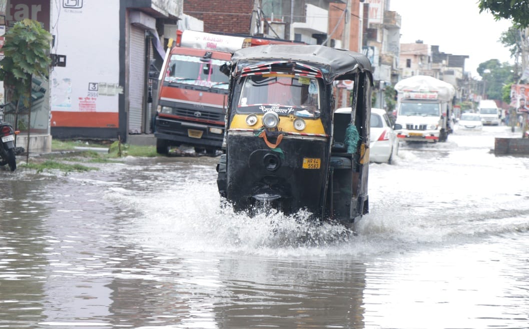 शक्ति नगर में बारिश में हुए जलभराव के बीच गुजरती कार। संवाद