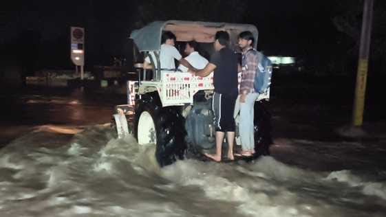 ट्रैक्टर की मदद से लोगों को दूसरे छोर तक पहुंचाते ग्रामीण। संवाद