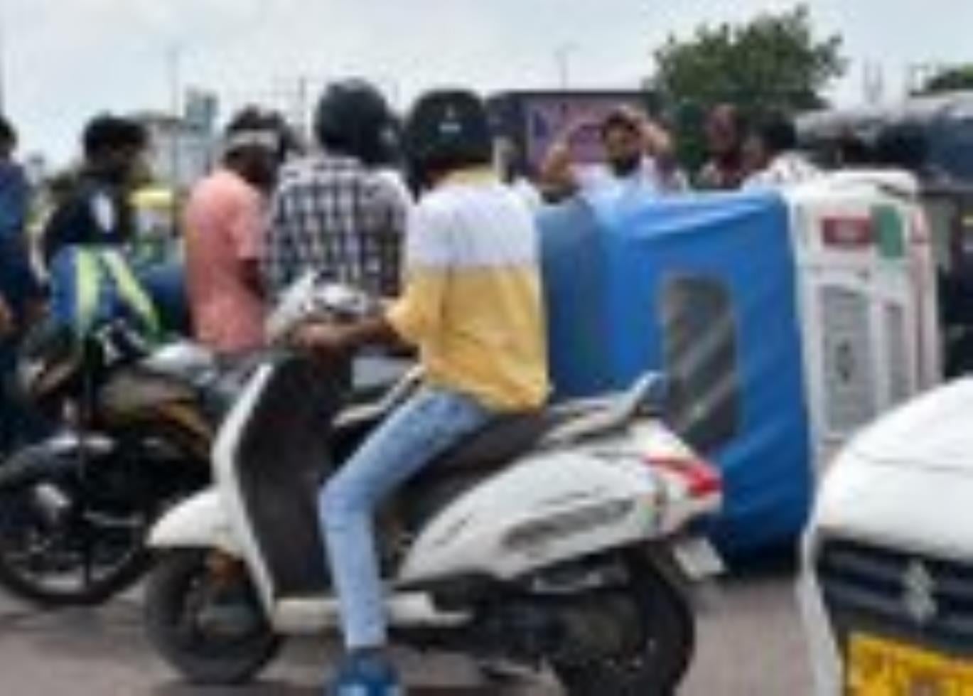 1090 चौराहे पर पलटी ऑटो में बैठी सवारियों को बाहर निकालते लोग।