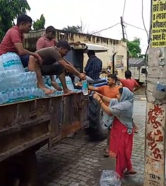 साहा के ग्रामीण इलाकों में लोगों को पानी की बोतल वितरित करते समाजसेवी। संवाद