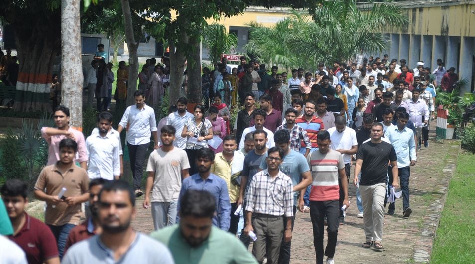 पीईटी की परीक्षा देने के लिए बूंदाबांदी में परीक्षा केंद्र पर लाइन में खड़े परीक्षार्थी। संवाद पीईटी की परीक्षा देने के लिए बूंदाबांदी में परीक्षा केंद्र पर लाइन में खड़े परीक्षार्थी। संवाद