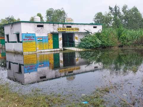 बरखेड़़ा क्षेत्र में स्कूल में पानी भरा होने के कारण एक निजी घर के बाहर बैठकर पढ़ते बच्चे। संवा