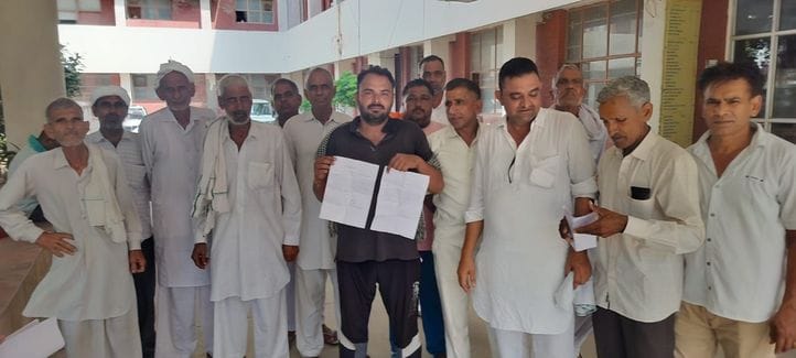 11जेएनडी15: खेतों में भरे पानी की गहराई दिखाते हुए किसान। किसान
