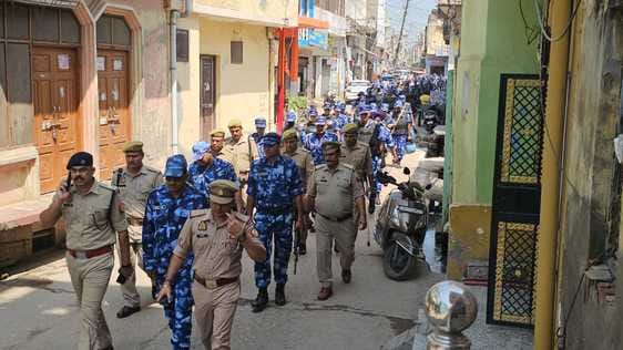 सरूपुर। कस्बा हर्रा में फ्लैग मार्च करती पुलिस। संवाद