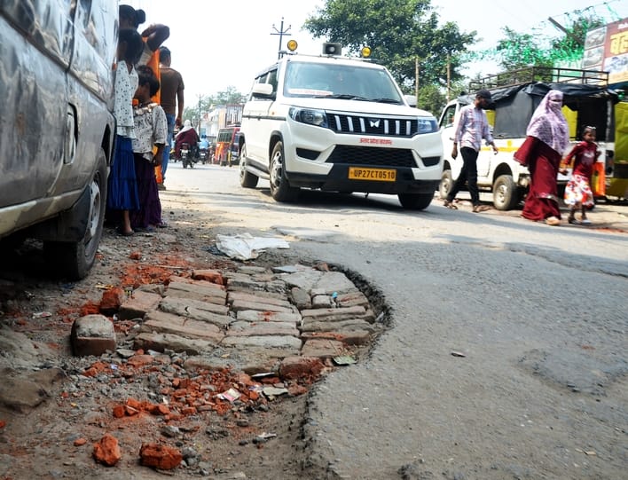 अशफाक नगर चौकी के पास सड़क पर उखड़ी पड़ी बजरी। संवाद
