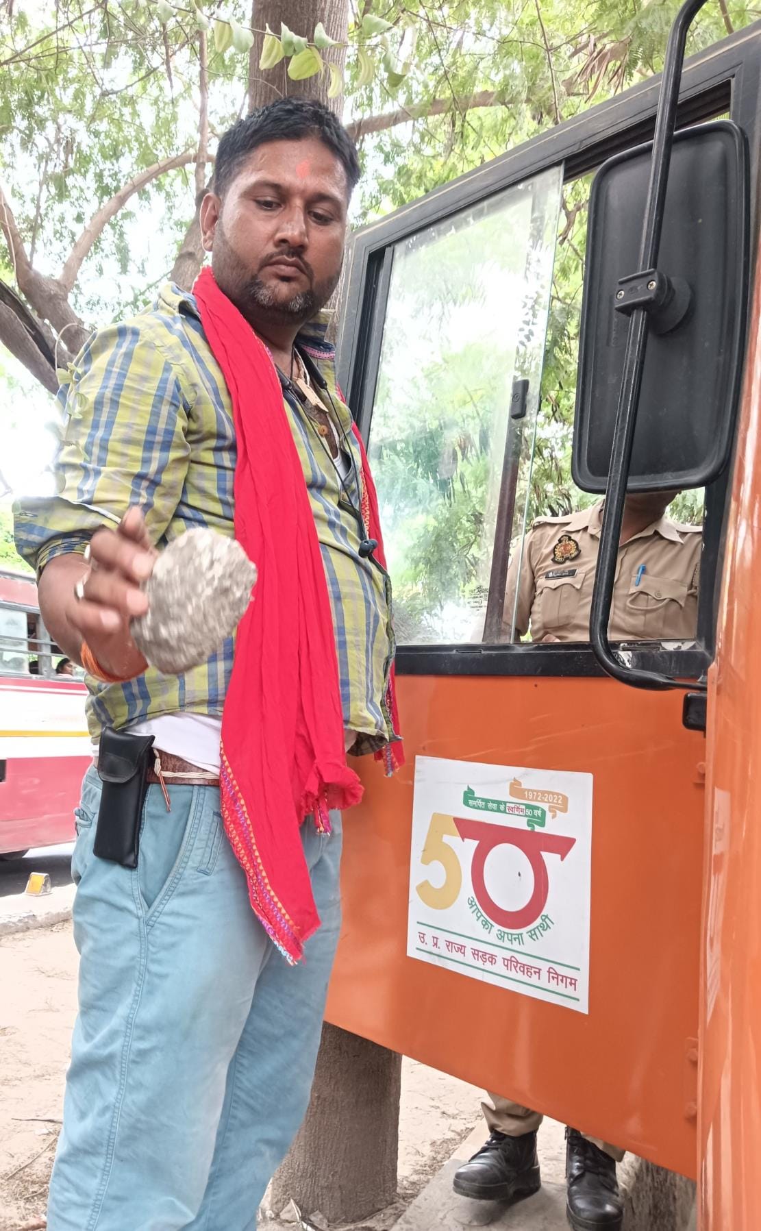 घटना की जांच करती पुलिस व पत्थर दिखाता बस चालक। घटना की जांच करती पुलिस व पत्थर दिखाता बस चालक।