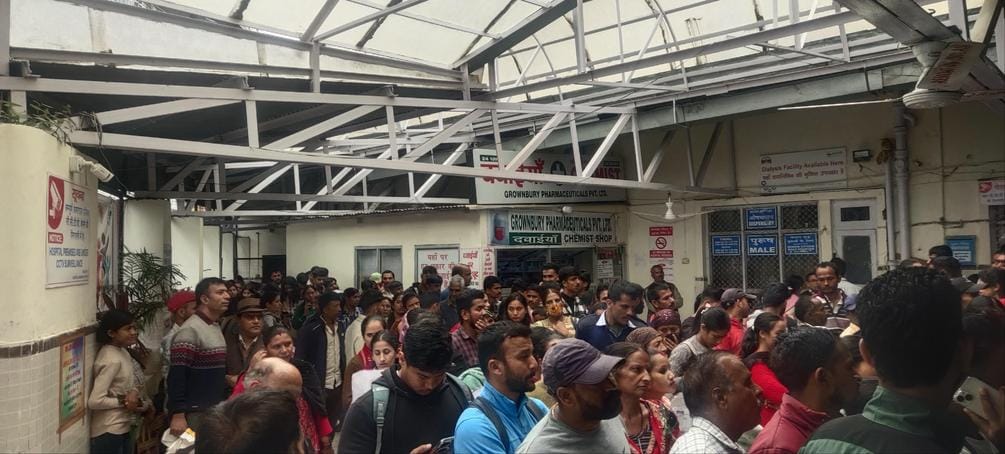 सोलन अस्पताल में इलाज के लिए पहुंचे लोग, बैंच पैक होने पर फर्श पर बैठकर बारी का इंतजार करते हुए