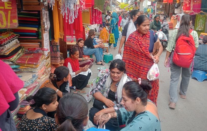 फोटो 25- सोनीपत की कच्चे क्वार्टर मार्केट में आगरा से आए युवाओं से मेहंदी लगवाती महिलाएं। संवाद