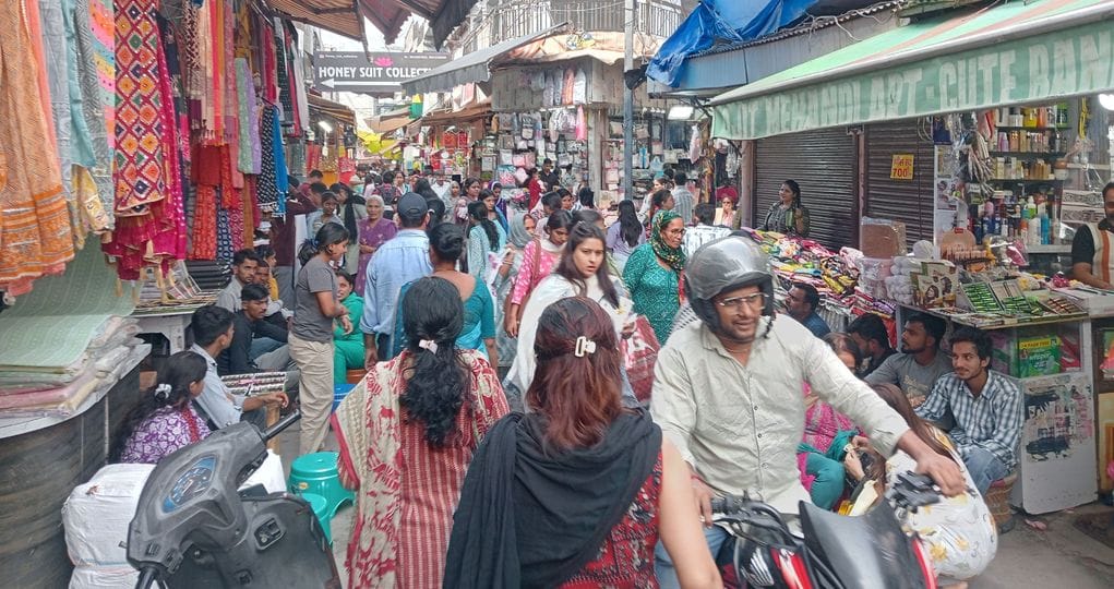 फोटो 25- सोनीपत की कच्चे क्वार्टर मार्केट में आगरा से आए युवाओं से मेहंदी लगवाती महिलाएं। संवाद