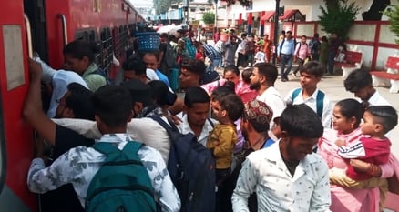 शाहजहांपुर रेलवे स्टेशन पर ट्रेन के गेट पर लटक कर जाते यात्री। संवाद