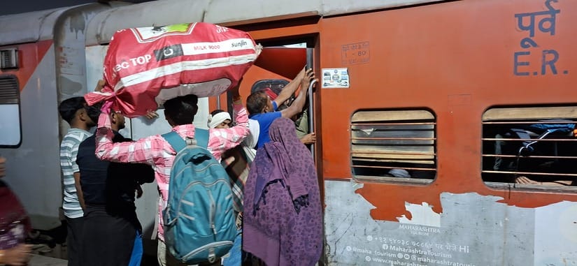 भीड़ के कारण ट्रेन के गेट पर लटके यात्री। संवाद भीड़ के कारण ट्रेन के गेट पर लटके यात्री। संवाद
