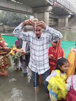 शाहजहांपुर में खन्नौत नदी तट पर पानी में खड़े होकर सूरज की पूजा करती महिला। संवाद