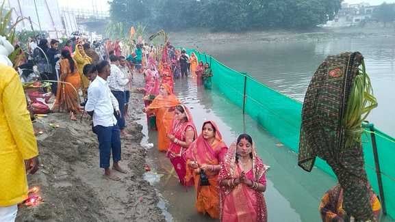 शाहजहांपुर में खन्नौत नदी तट पर पानी में खड़े होकर सूरज की पूजा करती महिला। संवाद
