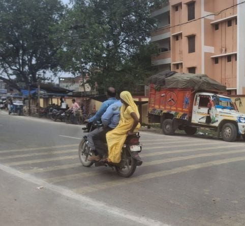तीन सवारी बिना हेलमेट बाइक सवार।  किसी का डर नहीं। संवाद