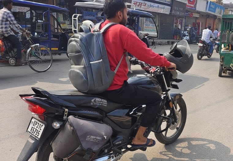 आंबेडकर पार्क के पास परिवार को बैठकर हेलमेट हैंडल में टांगकर जाते बाइक सवार। संवाद