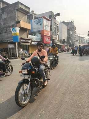 कांट में हाथ में हेलमेट लेकर जाता बाइक में पीछे बैठा युवक। संवाद